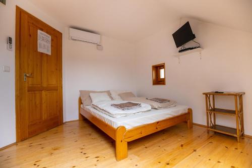 a small bedroom with a bed and a wooden door at NOBLE'S Panzió és Étterem in Nemesnép