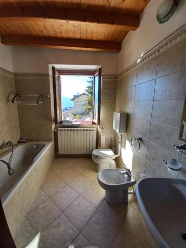 a bathroom with a toilet and a tub and a sink at casa vacanza da ghislin in Teglio