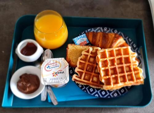 a blue tray with waffles and a glass of orange juice at LE MANGUIER in Baie-Mahault