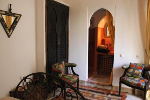 a living room with a chair and a black door at Riad Jnan El Cadi in Marrakech
