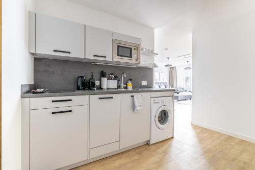 a white kitchen with a washing machine and a microwave at limehome Klagenfurt Karfreitstraße in Klagenfurt