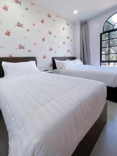 two beds in a hotel room with white walls at Hotel Decentraland Kuala Terengganu in Kuala Terengganu