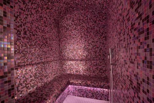 a red tiled bathroom with a tub with pink lights at Hôtel Victor Hugo Paris Kléber in Paris