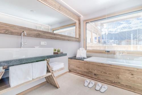 a bathroom with a large tub and a large window at Hotel Col Alto in Corvara in Badia