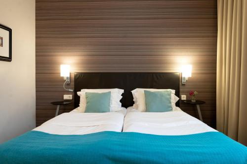 a large bed with blue and white sheets and pillows at Elite Stadshotellet Karlstad, Hotel & Spa in Karlstad