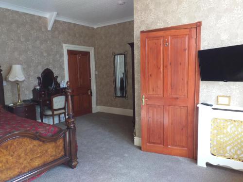a room with a bed, a chair and a door at St David's Guesthouse in Haverfordwest