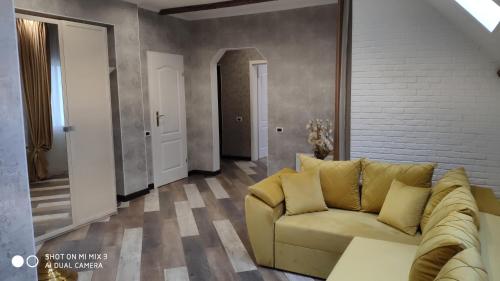 a living room with a yellow couch and a brick wall at White House in Bălţi