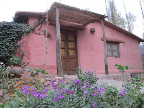 a pink house with a wooden door and flowers at La Calabaza Cabaña in Tilcara