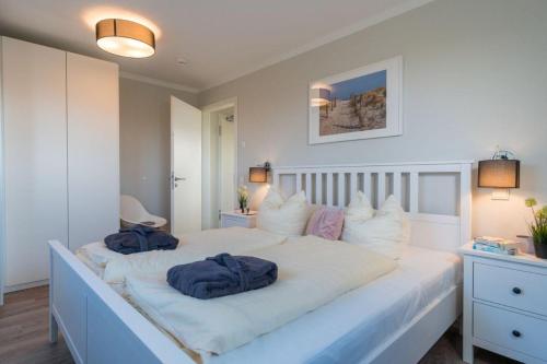 ein großes weißes Bett mit zwei blauen Handtüchern darauf in der Unterkunft Apartmenthaus "Kiki", Wohnung "Traumbude" in Heiligenhafen
