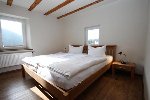 a bedroom with a bed with white sheets and two windows at Gasthaus Pension Geimer in Plütscheid