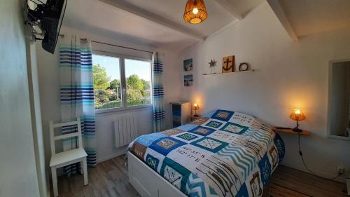 een kleine slaapkamer met een bed en een raam bij Maison Cormoran in Saint-Hilaire-de-Riez