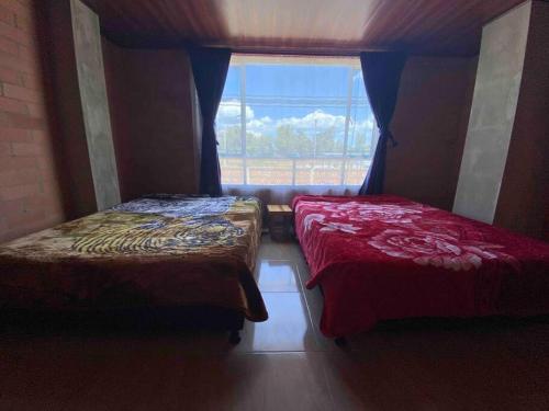2 Betten in einem Zimmer mit Fenster in der Unterkunft Hotel Villa Stella "Apartamentos y habitaciones" in Paipa