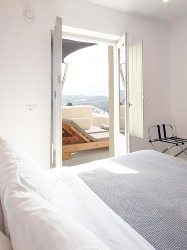 a bedroom with a bed and a view of a balcony at Caldera Cliff Illusion in Fira