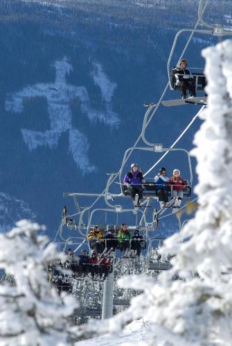 a group of people riding a ski lift in the snow at Ski and Bike-In and Out in Hafjell