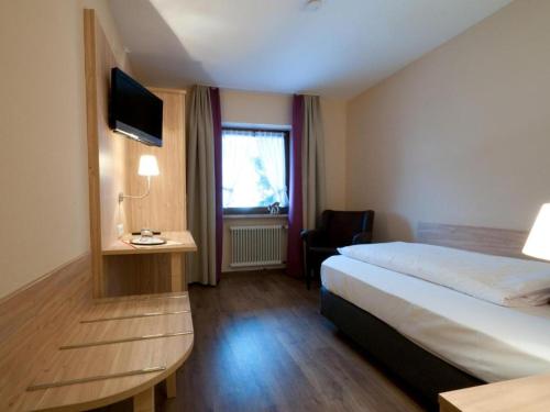 Habitación de hotel con cama y TV en Hotel-Gasthof Sperrer en Grassau