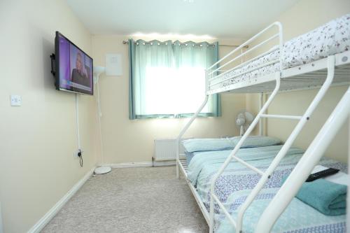 a bedroom with a bunk bed and a tv at Lovely 4 Bed House London in London