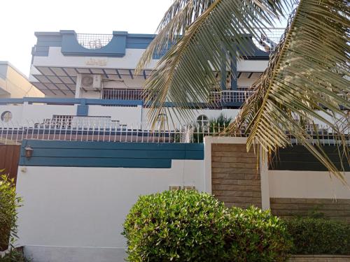 a white and blue building with a fence and trees at Seaview Lodge Guest House in Karachi