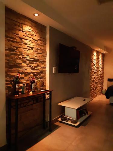 a room with a stone wall with a table and a tv at Estación Libertad in Perito Moreno