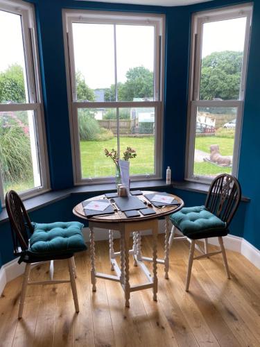 a table and two chairs in a room with windows at East Llanteg Guest House in Amroth