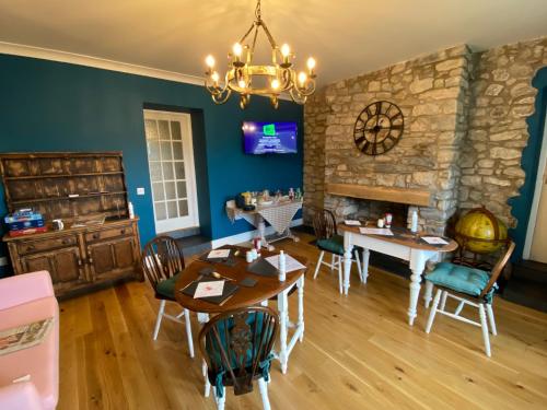 a dining room with a table and a stone fireplace at East Llanteg Guest House in Amroth