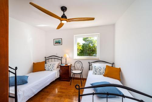 a bedroom with two beds and a ceiling fan at Golubinka Apartments in Veli Rat