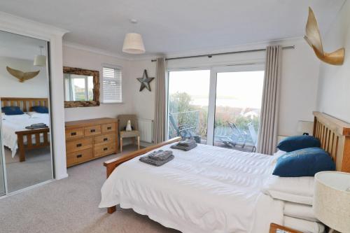 a bedroom with a large white bed and a balcony at Holiday home with Estuary Views, parking & balcony in Padstow