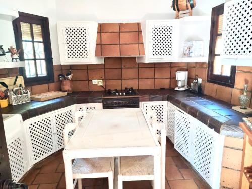 cocina con armarios blancos, mesa y sillas en Chalet rural en La Mancha con jardin y piscina privados, en Tomelloso