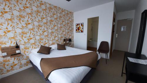 a bedroom with a bed with a floral wallpaper at Au Bon Accueil in Perros-Guirec