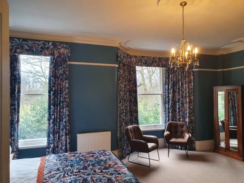 a bedroom with a bed and two chairs and windows at Bronte Guest House in York