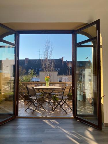 una porta-finestra aperta con tavolo e sedie sul balcone. di Ferienwohnung Bienengarten a Bingen am Rhein