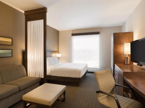 a small hotel room with a bed and a couch at Hyatt Place San Jose Pinares in San José