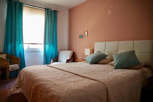 a bedroom with a large bed with blue curtains and a window at Family and Friends , Familienapartment Playa de San Juan in Guía de Isora