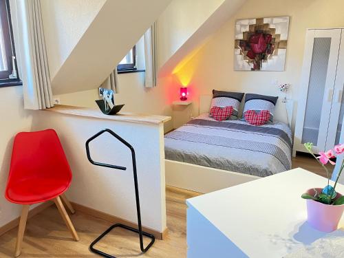 - une petite chambre avec un lit et un fauteuil rouge dans l'établissement Gite St Léon à Eguisheim, à Eguisheim