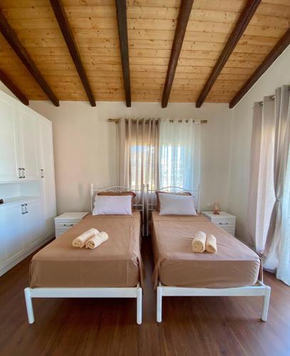 two beds in a room with wooden ceilings at Tani's House in Sarandë