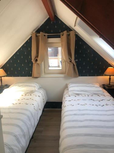 two beds in a small room with a window at De Spaier 3a in Zoutelande