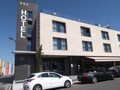 un coche blanco estacionado frente a un edificio en Hotel Río Hortega en Valladolid