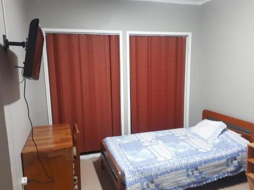 a bedroom with a bed and a tv and curtains at Hostal Copa Arica in Arica