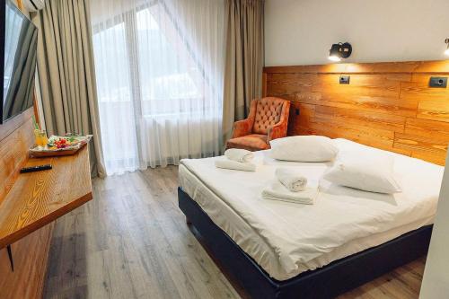 um quarto com uma cama grande e uma cadeira em Popasul Domnesc- Resort& Spa- Voronet Vue em Voronet