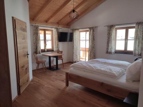 a bedroom with a bed and a desk and windows at Landhaus Hutter in Bad Heilbrunn