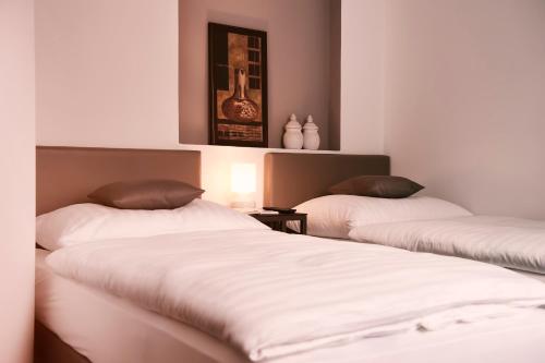 two beds in a room with white sheets and brown pillows at Villa na Vinici in Prague