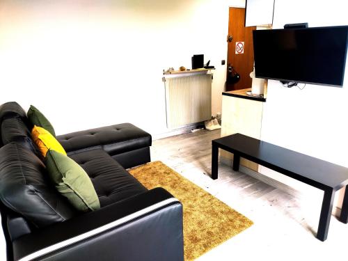 a living room with a black leather couch and a table at 36 Dajot Boutique Apartment - 70 in Melun