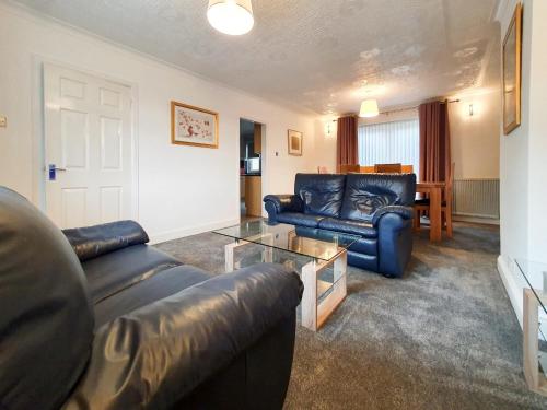 a living room with two leather couches and a table at 3 bedroom house Amazon M90 Dunfermline Edinburgh in Fife