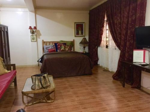 um quarto com uma cama e uma televisão em The Saint Joseph Residential Suites em Lucena