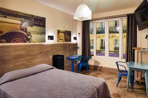 a bedroom with a bed and a table and chairs at Hôtel de Roubaix in Paris