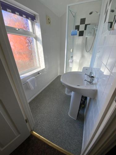 a white bathroom with a sink and a window at The Laurels Hotel in Skegness