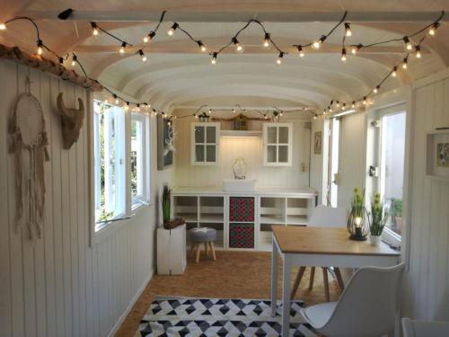 a kitchen with a table and lights on a ceiling at Zurück zur Natur - Urlaub im Zirkuswagen, Sommeratelier oder Schindelwagen in Adenbach