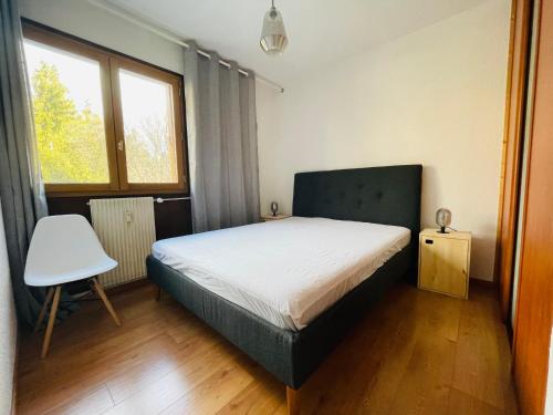 ein Schlafzimmer mit einem Bett, einem Stuhl und einem Fenster in der Unterkunft Appartement rénové à 200m de la plage + garage in Embrun