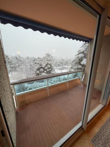 einen Balkon mit einer Glasschiebetür und Aussicht in der Unterkunft Appartement rénové à 200m de la plage + garage in Embrun