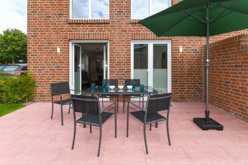 a table with chairs and an umbrella on a patio at Ferienhaus Licht in Dornumersiel