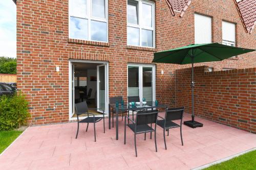 a patio with a table and chairs and an umbrella at Ferienhaus Licht in Dornumersiel